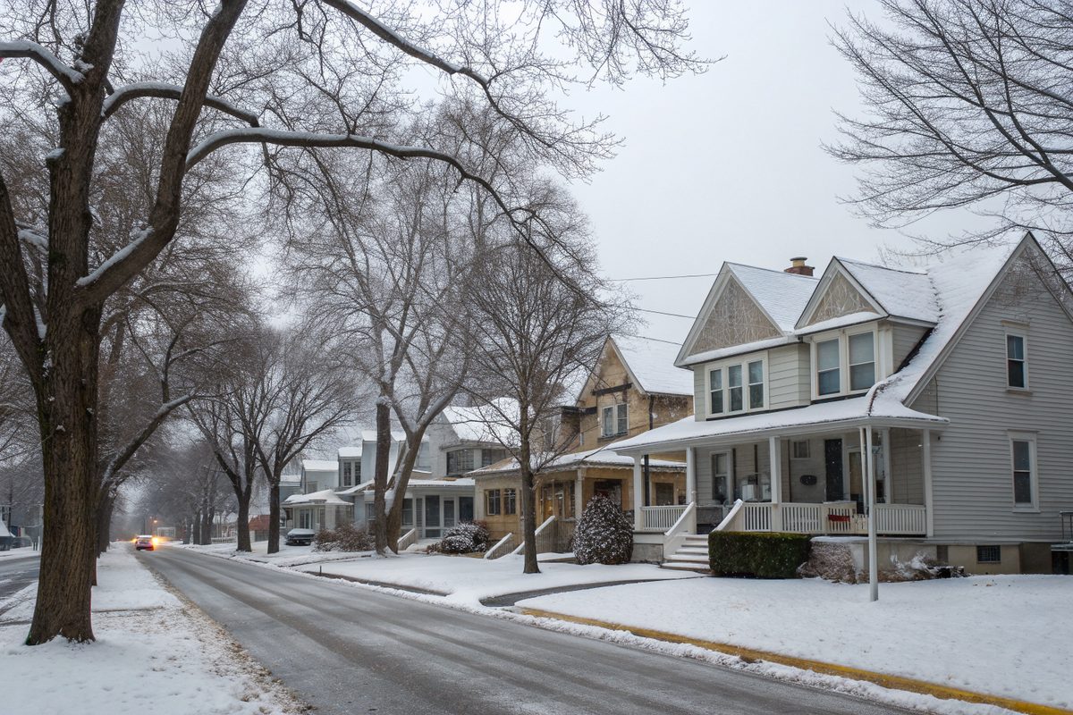 Snow on the roofs and lawns of older two-story houses on a quiet winter street